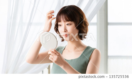 Woman looking in the mirror, beauty image 135725536