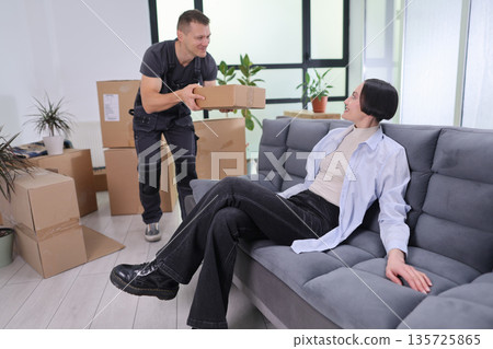 Moving day joy as a couple unpacks boxes and sets up their new home in a bright, cozy room filled with plants 135725865