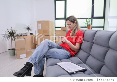 Relaxing moment in a modern apartment surrounded by moving boxes and plants Relaxing moment in a modern apartment surrounded by moving boxes and plants 135725875