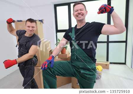 Joyful movers celebrating their hard work in a bright, modern living space filled with boxes Joyful movers celebrating their hard work in a bright, modern living space filled with boxes 135725910