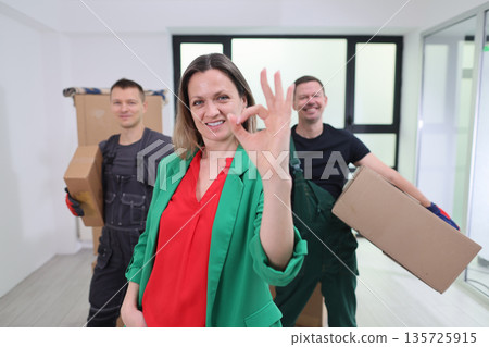 Movers and happy client celebrating successful relocation in bright modern apartment 135725915