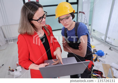 Collaborative planning session between a businesswoman and construction worker indoors Collaborative planning session between a businesswoman and construction worker indoors 135726131