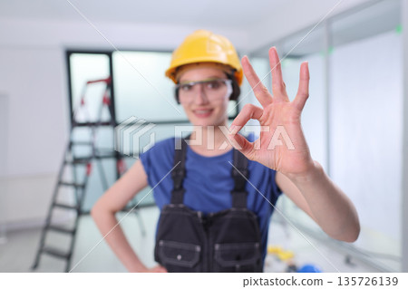 Skilled worker shows approval with a gesture, ready to take on the next construction challenge in a modern building space Skilled worker shows approval with a gesture, ready to take on the next construction challenge in a modern building space 135726139