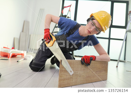 Skilled worker measures wooden plank while kneeling on floor in bright, modern workspace Skilled worker measures wooden plank while kneeling on floor in bright, modern workspace 135726154
