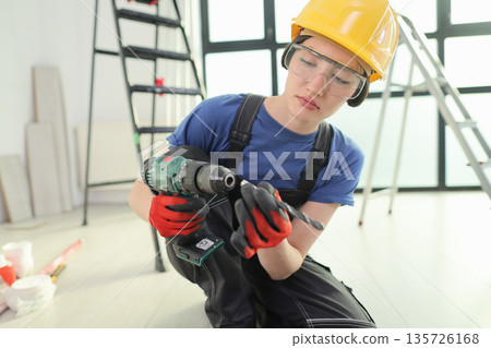 Skilled young worker carefully inspects a power drill while preparing for a project indoors 135726168