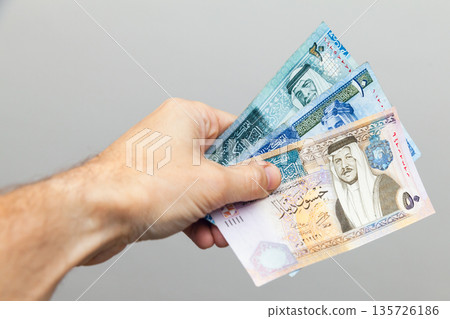 A close-up of a hand gripping a fan of Jordanian dinars A close-up of a hand gripping a fan of Jordanian dinars 135726186