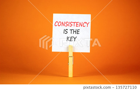 Consistency is the key symbol. Concept words Consistency is the key on beautiful white paper on wooden clothespins. Beautiful orange background. Business consistency is the key concept. Copy space. 135727110