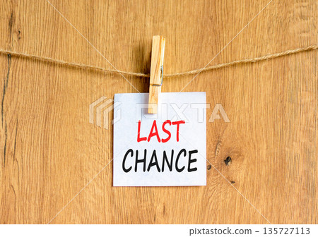Last chance symbol. Concept word Last chance on beautiful white paper. Beautiful wooden clothespin. Beautiful wooden background. Business last chance concept. Copy space. Last chance symbol. Concept word Last chance on beautiful white paper. Beautiful wooden clothespin. Beautiful wooden background. Business last chance concept. Copy space. 135727113