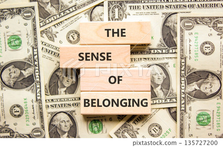 The sense of belonging symbol. Concept words The sense of belonging on beautiful wooden blocks. Beautiful background from dollar bills. Business and the sense of belonging concept. Copy space. 135727200