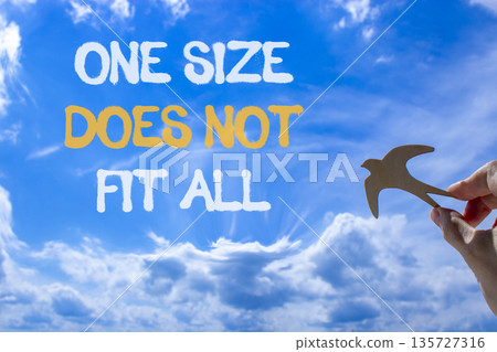 One size does not fit all symbol. Concept words One size does not fit all on beautiful sky. Beautiful blue sky background. Businessman's hand. Business one size does not fit all concept. Copy space. 135727316