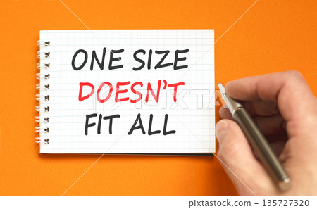 One size does not fit all symbol. Concept words One size does not fit all on beautiful note. Beautiful orange background. Businessman's hand. Business one size does not fit all concept. Copy space. One size does not fit all symbol. Concept words One size does not fit all on beautiful note. Beautiful orange background. Businessman's hand. Business one size does not fit all concept. Copy space. 135727320