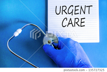 Urgent care symbol. Concept words Urgent care on beautiful white note. Doctor's hand in blue medical glove. Stethoscope. Beautiful blue background. Medical healthy lifestyle urgent care concept. Urgent care symbol. Concept words Urgent care on beautiful white note. Doctor's hand in blue medical glove. Stethoscope. Beautiful blue background. Medical healthy lifestyle urgent care concept. 135727325