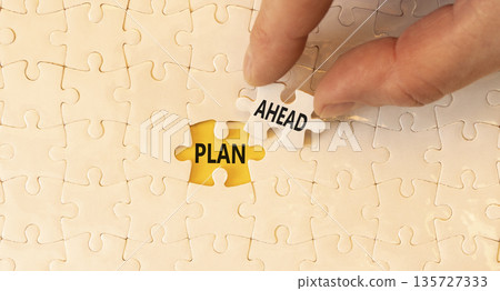 Plan ahead symbol. Concept word Plan ahead on beautiful white puzzles. Businessman's hand. Beautiful yellow paper background. Business plan ahead concept. Copy space. 135727333