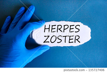 Herpes zoster symbol. Concept words Herpes zoster on beautiful white paper. Doctor's hand in blue medical glove. Beautiful blue background. Medical healthy lifestyle herpes zoster concept. 135727406