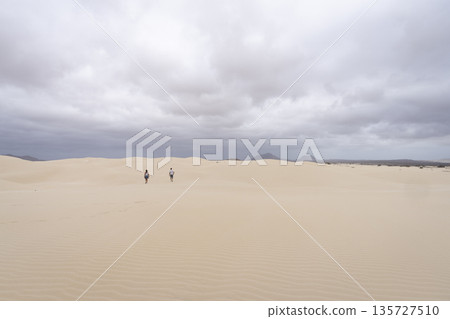 Two people walking in sand dunes in Viana desert at overcast day 135727510