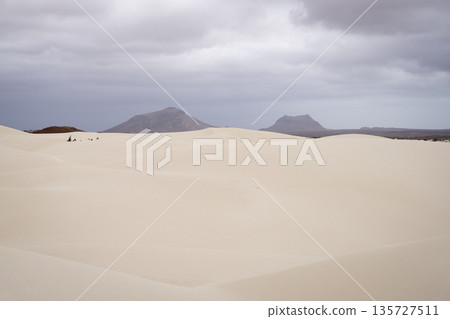 Sand dunes in Viana desert at overcast day and background volcanic mountains Sand dunes in Viana desert at overcast day and background volcanic mountains 135727511