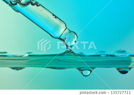 Pipette dripping blue liquid in science lab 135727711