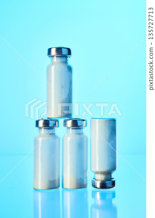 Vials containing medical powder against blue background Vials containing medical powder against blue background 135727713