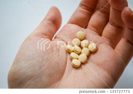 Human hand holding multiple yellow tablets Human hand holding multiple yellow tablets 135727773