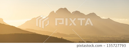 Golden morning mist obscures mountain peaks. Serene nature landscape with soft light. Atmospheric view for travel and outdoor design. Golden morning mist obscures mountain peaks. Serene nature landscape with soft light. Atmospheric view for travel and outdoor design. 135727793