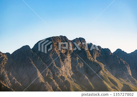 Rocky mountain peaks against a clear blue sky. Majestic nature landscape with dramatic slopes. Concept of adventure, travel. Rocky mountain peaks against a clear blue sky. Majestic nature landscape with dramatic slopes. Concept of adventure, travel. 135727802
