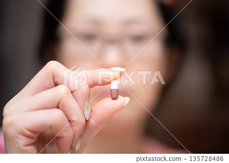 一名女子手持膠囊狀藥物 135728486