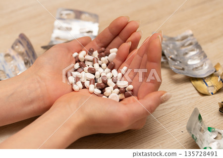 Woman's hand holding a lot of medicine Woman's hand holding a lot of medicine 135728491
