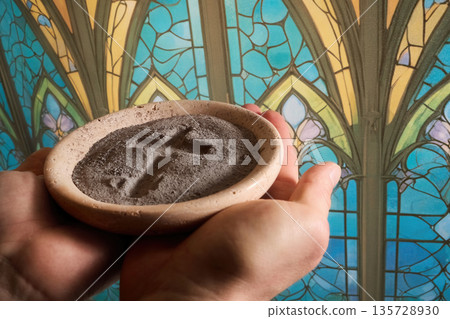 Hands holding ash wednesday ashes with stained glass background Hands holding ash wednesday ashes with stained glass background 135728930