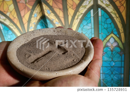 Hands holding ash wednesday ashes cross in church Hands holding ash wednesday ashes cross in church 135728931