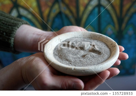Hands holding ash wednesday ashes with cross symbol Hands holding ash wednesday ashes with cross symbol 135728933