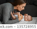 A young mother bent at the little baby, at home. 135728955