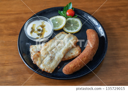 Grilled black cod fillets served with passion fruit sauce, lemon slices, and a crispy side, showcasing a delicious culinary presentation Grilled black cod fillets served with passion fruit sauce, lemon slices, and a crispy side, showcasing a delicious culinary presentation 135729015