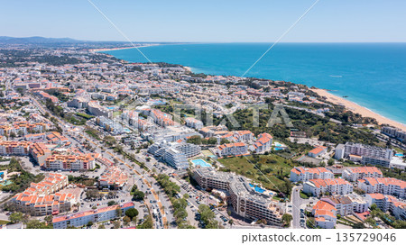 Visitors enjoy the vibrant atmosphere of Albufeira marina with buildings, beaches, and clear blue waters in Algarve, Portugal on a sunny day 135729046