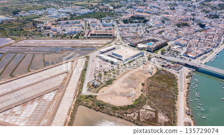 Tavira in Algarve with buildings, salt flats, a river, and parts of the ocean visible in the distance under sunny weather 135729074