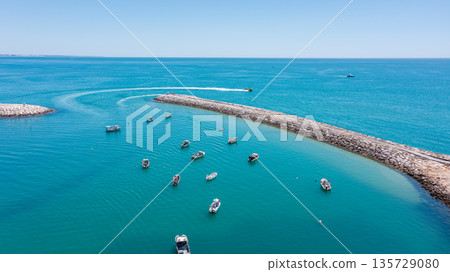 Boats are scattered in the marina of Albufeira with clear blue waters and a sunlit sky in Algarve, Portugal. Tourists enjoy the seaside during the day Boats are scattered in the marina of Albufeira with clear blue waters and a sunlit sky in Algarve, Portugal. Tourists enjoy the seaside during the day 135729080