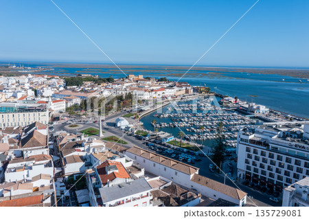 Visitors enjoy the lively dock area in Faro, Algarve, where boats are moored. The old town offers views over Ria Formosa and surrounding buildings Visitors enjoy the lively dock area in Faro, Algarve, where boats are moored. The old town offers views over Ria Formosa and surrounding buildings 135729081