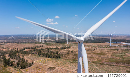 Wind green energy. Wind turbine stands tall against a clear blue sky, surrounded by vast fields and additional turbines, symbolizing renewable energy future 135729091