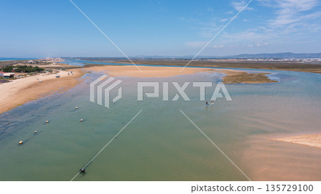 Drone captures Ria Formosa and Praia de Faro showing calm waters, sandy areas, and people engaging with nature in Faro, Portugal on a sunny day Drone captures Ria Formosa and Praia de Faro showing calm waters, sandy areas, and people engaging with nature in Faro, Portugal on a sunny day 135729100