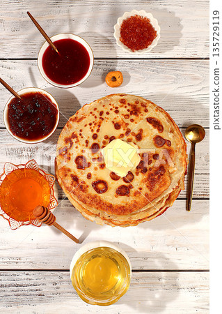 Delicious Russian pancakes with soft cheese, honey, jam, and sour cream on an elegant kitchen table. Maslenitsa concept and traditional Russian cuisine. Advertising banner for a cafe or restaurant Delicious Russian pancakes with soft cheese, honey, jam, and sour cream on an elegant kitchen table. Maslenitsa concept and traditional Russian cuisine. Advertising banner for a cafe or restaurant 135729119
