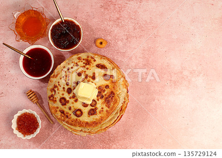 Maslenitsa concept and traditional Russian cuisine. Delicious Russian pancakes with soft cheese, honey, jam, and sour cream on an elegant kitchen table. Advertising banner for a cafe or restaurant. Maslenitsa concept and traditional Russian cuisine. Delicious Russian pancakes with soft cheese, honey, jam, and sour cream on an elegant kitchen table. Advertising banner for a cafe or restaurant. 135729124