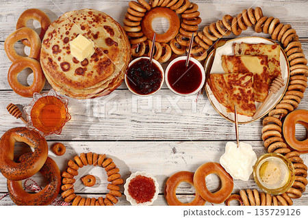 Maslenitsa concept and traditional Russian cuisine.Delicious Russian pancakes with soft cheese, honey, jam, sour cream, caviar and bagels, pretzels on the festive table.Advertising banner for a cafe 135729126