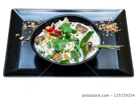 Colorful vegan Thai seitan curry served in a black bowl, garnished with fresh herbs and vegetables, showcasing vibrant culinary presentation Colorful vegan Thai seitan curry served in a black bowl, garnished with fresh herbs and vegetables, showcasing vibrant culinary presentation 135729154