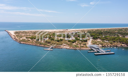 Aerial view of serene coastal landscape featuring sandy beach, lush greenery, and tranquil waters, ideal for relaxation and nature exploration. Tavira Portugal Algarve Aerial view of serene coastal landscape featuring sandy beach, lush greenery, and tranquil waters, ideal for relaxation and nature exploration. Tavira Portugal Algarve 135729158