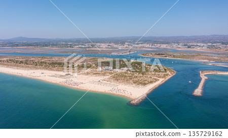 Aerial view of a serene beach with golden sands and turquoise waters, showcasing natural beauty and tranquil atmosphere. Tavira Portugal Algarve 135729162