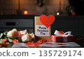 Rose petals scattered on a table with a bouquet of flowers, a Valentines card and a gift box. Cozy festive setting 135729174