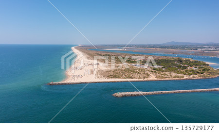 Aerial view of serene beach landscape with golden sand and turquoise waters, showcasing natural beauty and tranquility in coastal environment. Tavira Portugal Algarve Aerial view of serene beach landscape with golden sand and turquoise waters, showcasing natural beauty and tranquility in coastal environment. Tavira Portugal Algarve 135729177