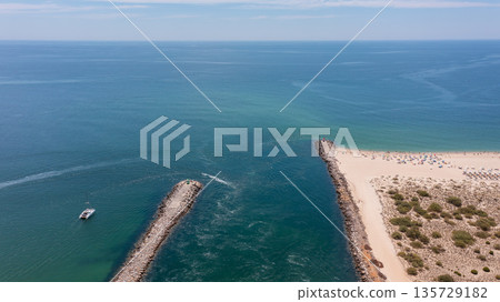 Scenic coastal view featuring tranquil waters, sandy beach, and distant boat, capturing the essence of a serene seaside escape. Tavira Portugal Algarve 135729182