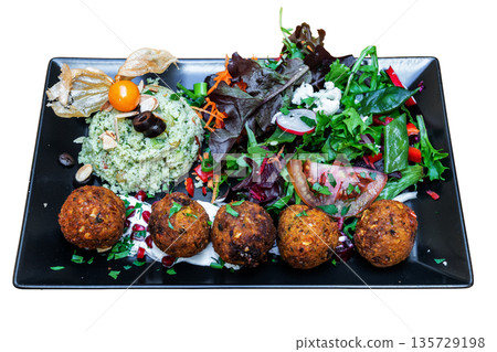 Colorful vegan Moroccan tabbouleh served on a black plate, featuring fresh greens, herbs, and flavorful falafel balls, perfect for healthy dining Colorful vegan Moroccan tabbouleh served on a black plate, featuring fresh greens, herbs, and flavorful falafel balls, perfect for healthy dining 135729198