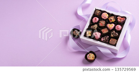 Assorted gourmet chocolates in gift box with ribbon, pink background Assorted gourmet chocolates in gift box with ribbon, pink background 135729569