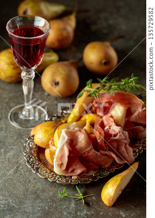Prosciutto with pears and thyme on a silver tray. 135729582